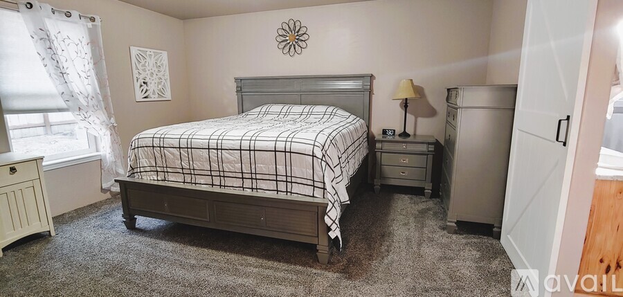 A bedroom with a bed, nightstand, and dresser.