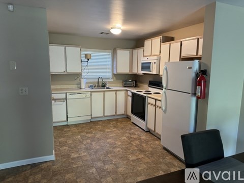 A kitchen with white appliances and a black chair.
