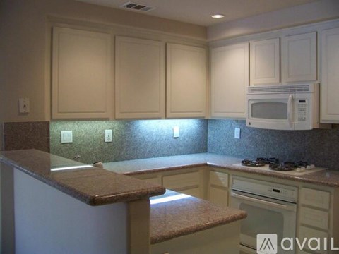 A kitchen with white cabinets and a brown countertop.