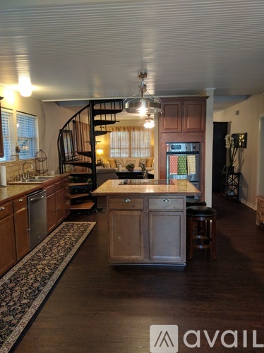 A kitchen with wooden cabinets and a spiral staircase.