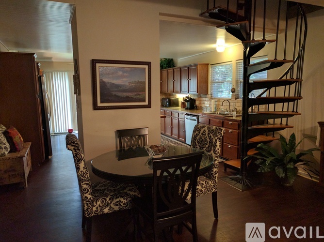 A dining room with a table and chairs and a spiral staircase.
