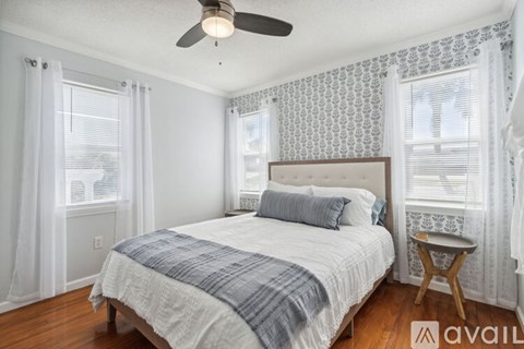 A bedroom with a bed, a ceiling fan, and a window with curtains.