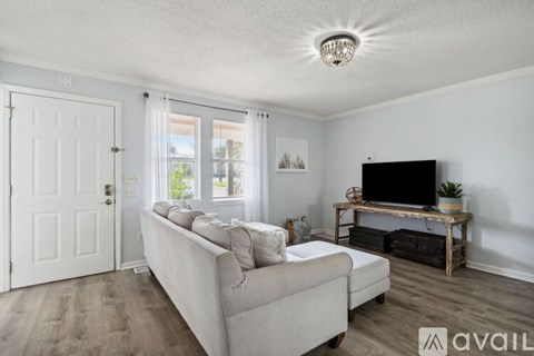A living room with a white couch and a flat screen TV.