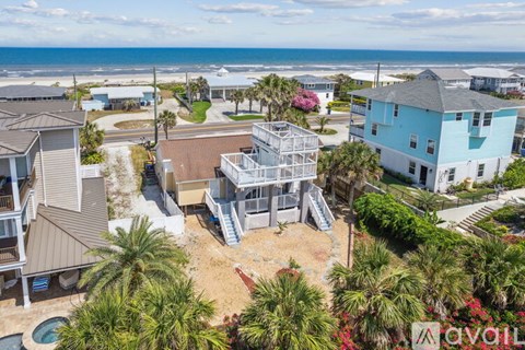 A bird's eye view of a beachfront property with a pool and a house with a blue roof.