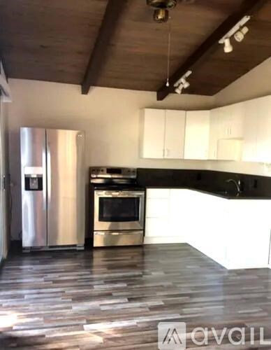 A kitchen with a stainless steel refrigerator and wooden flooring.
