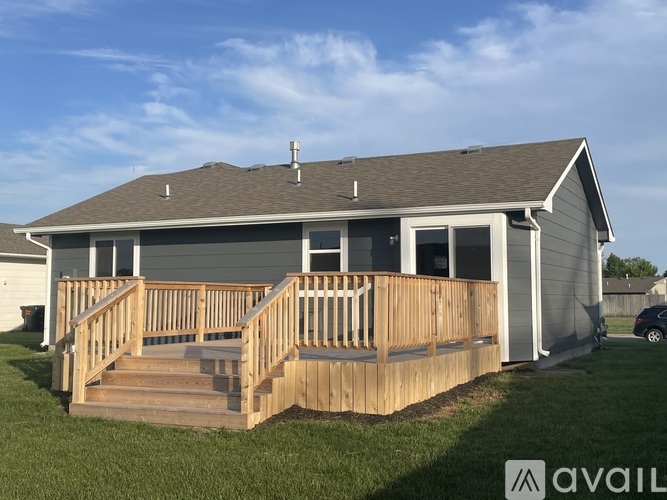 A house with a wooden deck and a car parked in the driveway.