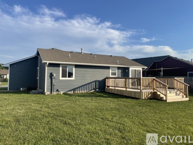 A house with a grey exterior and a wooden deck is available for purchase.