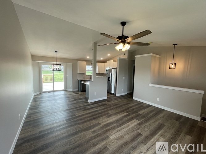 A spacious room with a ceiling fan and wooden flooring.