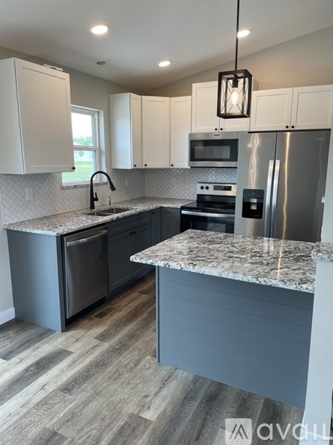A kitchen with a marble countertop and stainless steel appliances.
