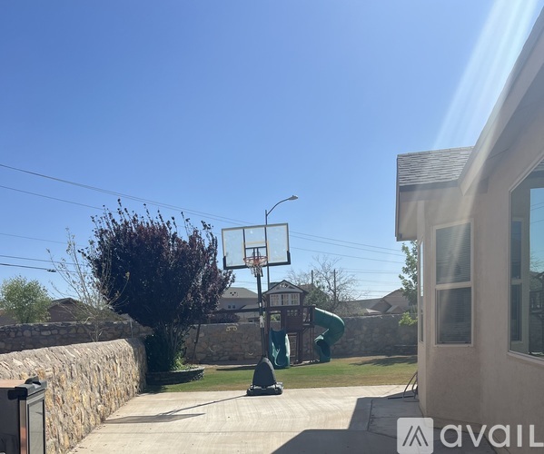 A basketball hoop is in the backyard of a house.