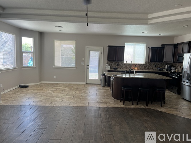 A spacious kitchen and living room with dark wood flooring and modern appliances.