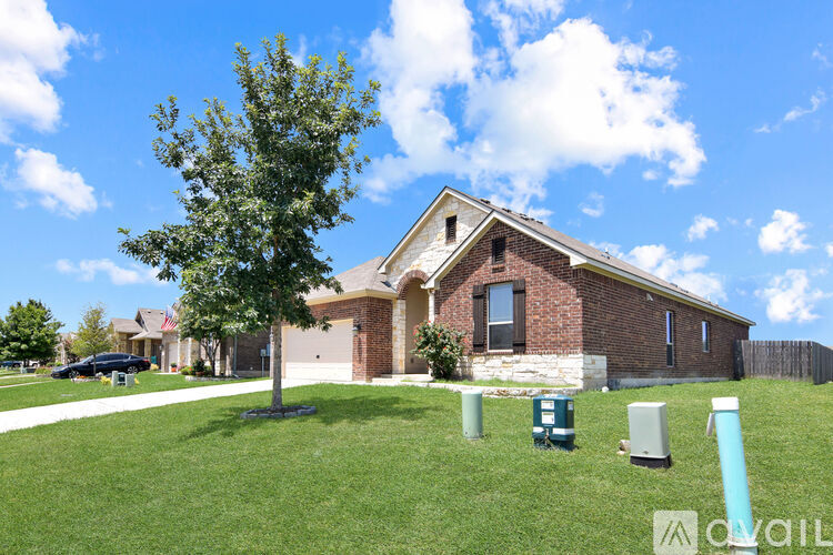 A house with a green lawn and a tree in front of it.