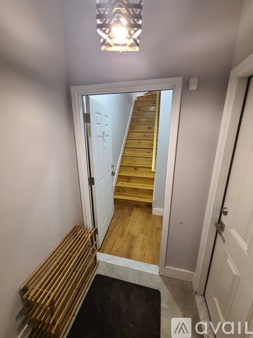 A hallway with a wooden staircase and a white door.