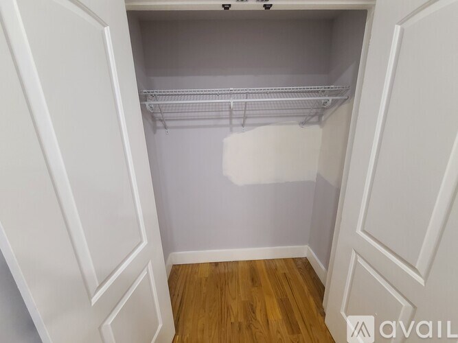 A white closet with a wooden floor and white walls.