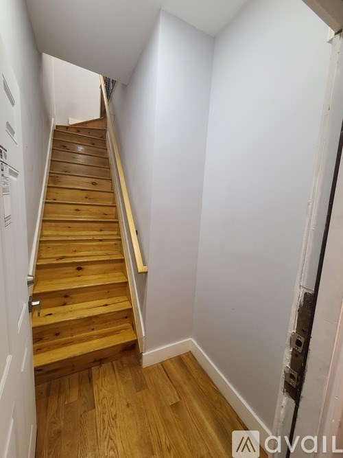 A wooden staircase with a white wall on one side and a door on the other.
