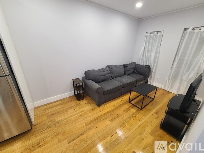 A living room with a grey couch and a wooden floor.