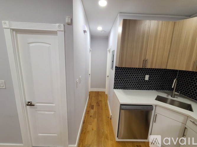 A kitchen with a white door and a trash can.