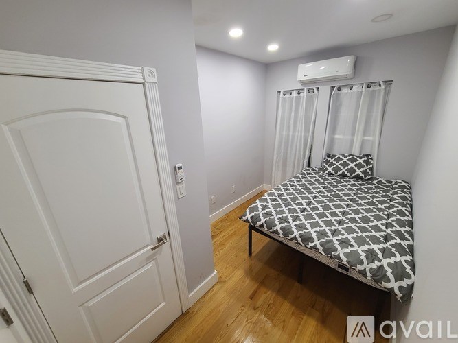 A bedroom with a bed, a door, and a window with blinds.