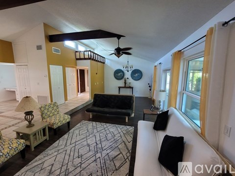A living room with a black couch and a patterned rug.
