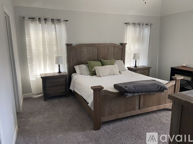 A bedroom with a large bed and two nightstands.