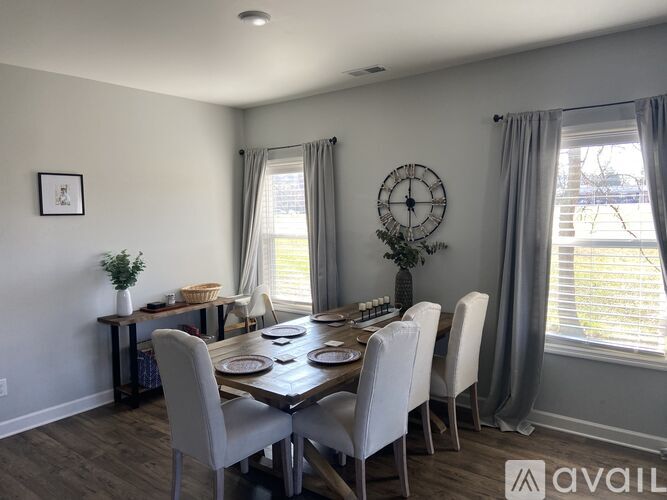 A dining room with a table set for six and a clock on the wall.