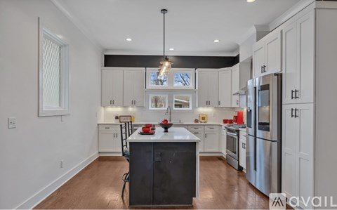 A kitchen with white cabinets and a black island.