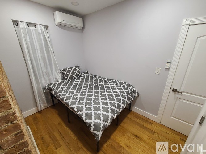 A bedroom with a bed, wooden floor, and a white door.