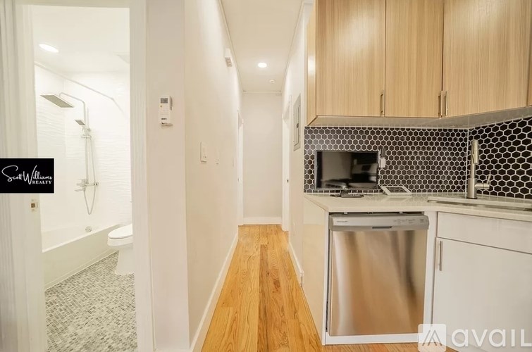 A kitchen with a stainless steel dishwasher and wooden cabinets.