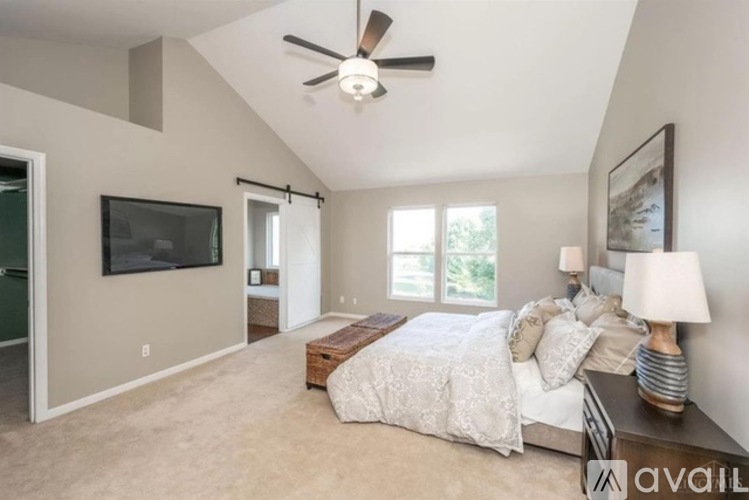 A bedroom with a bed, a television, and a ceiling fan.