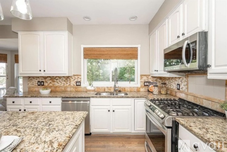 A kitchen with granite countertops and white cabinets.