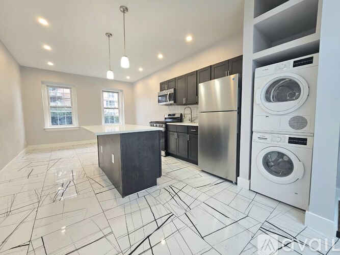 A modern kitchen with a black island and stainless steel appliances.