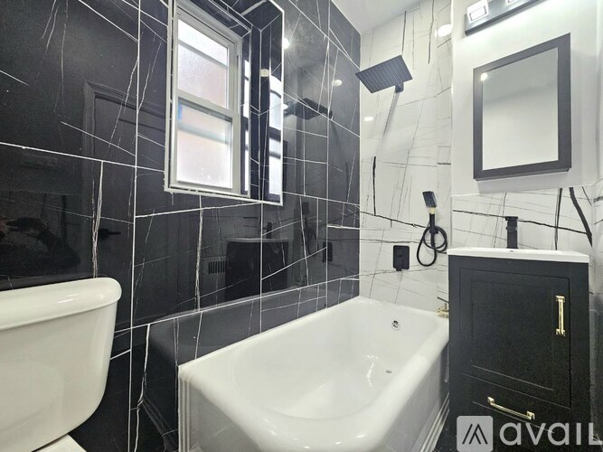 A bathroom with a white tub and black tiles.