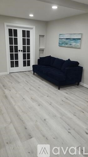 A living room with a black couch and a wooden floor.