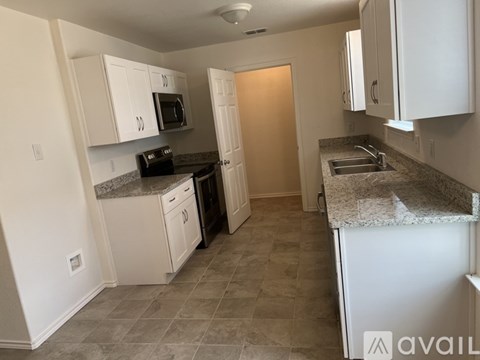 A kitchen with white cabinets and a granite countertop.