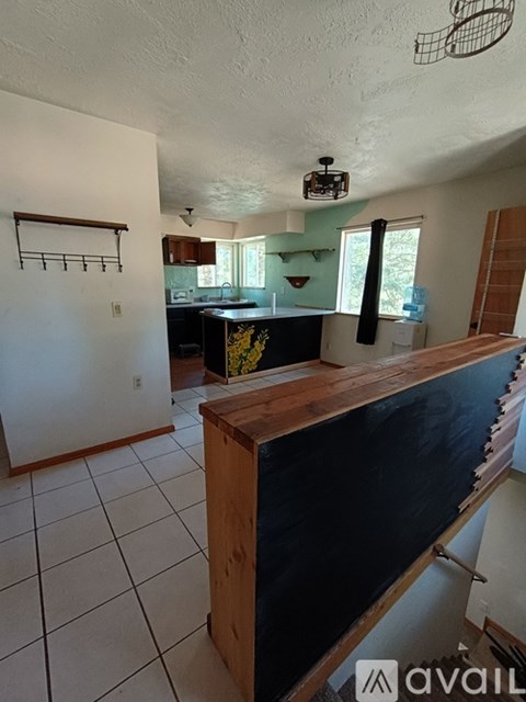 A kitchen with a black counter top and a wooden bar.