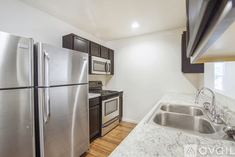 A kitchen with a stainless steel refrigerator, microwave, oven, and sink.