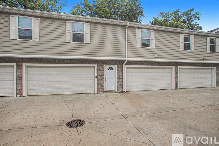 A row of houses with garages and a tree in the background.