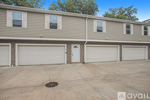 A row of houses with garages and a tree in the background.