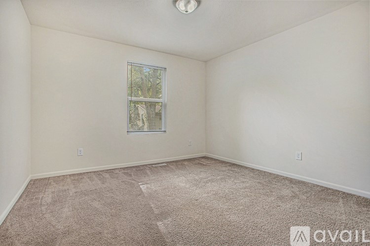 A room with a carpeted floor and a window with blinds.