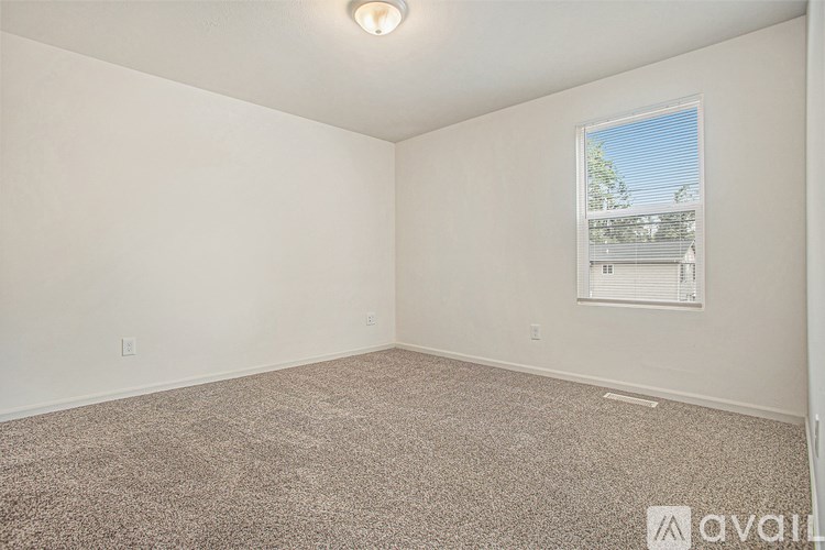 A room with a carpeted floor and a window showing a building outside.