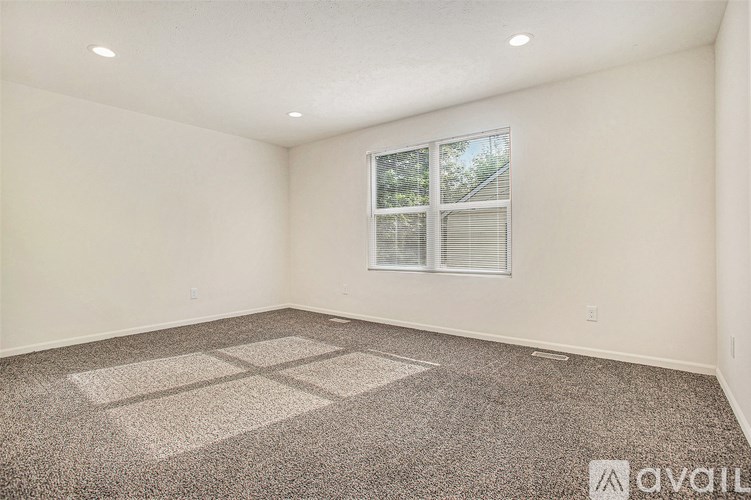 A room with a large window and a carpeted floor.
