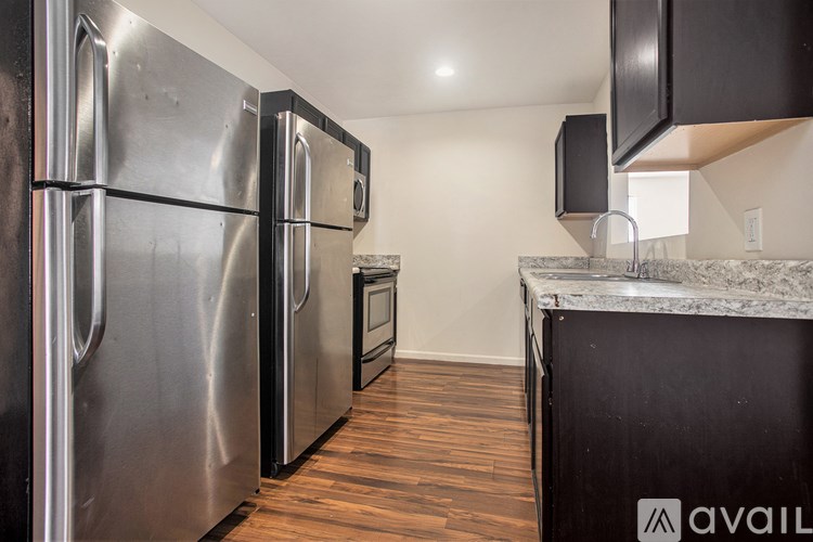 A kitchen with a stainless steel refrigerator and a granite countertop.