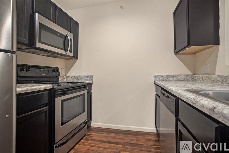 A kitchen with black appliances and wooden floors.