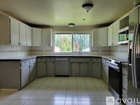 A kitchen with white cabinets and appliances is available for rent.