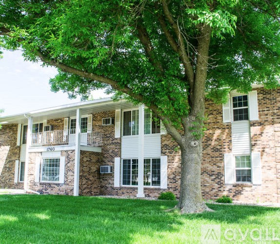A tree in front of a brick building with the number 1760 on it.