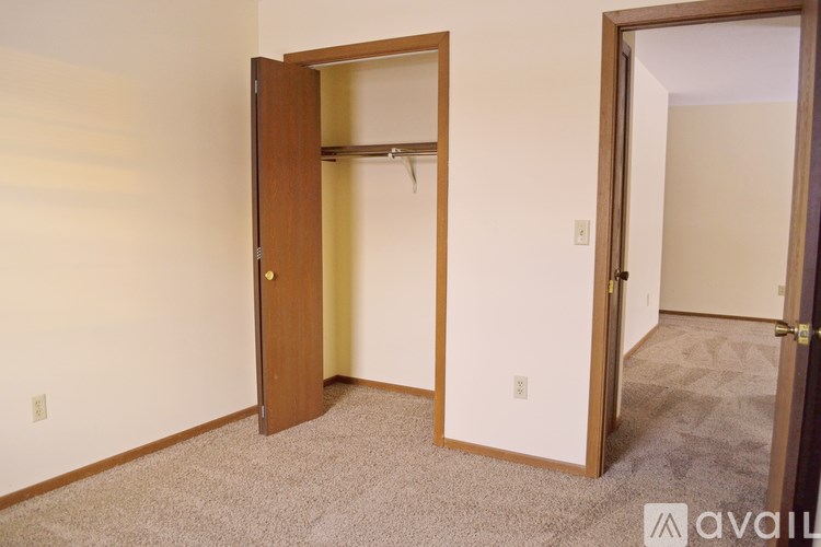 A room with a carpeted floor and two doors, one of which is open.