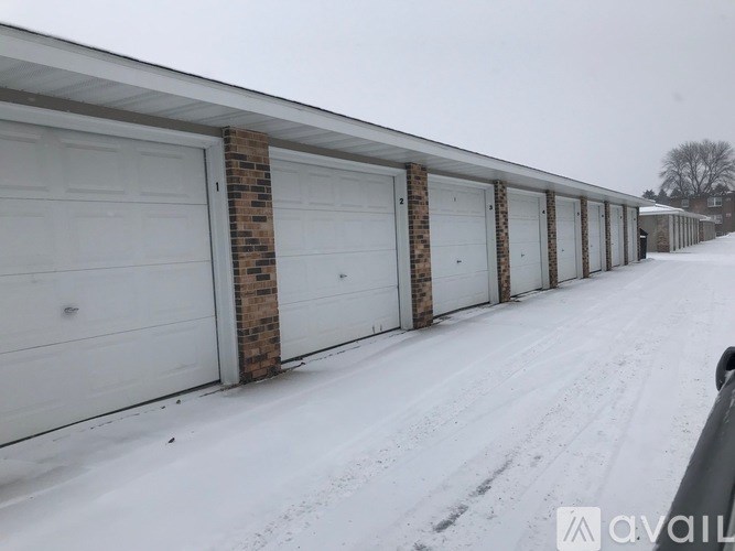 A row of garage doors are closed and covered in snow.