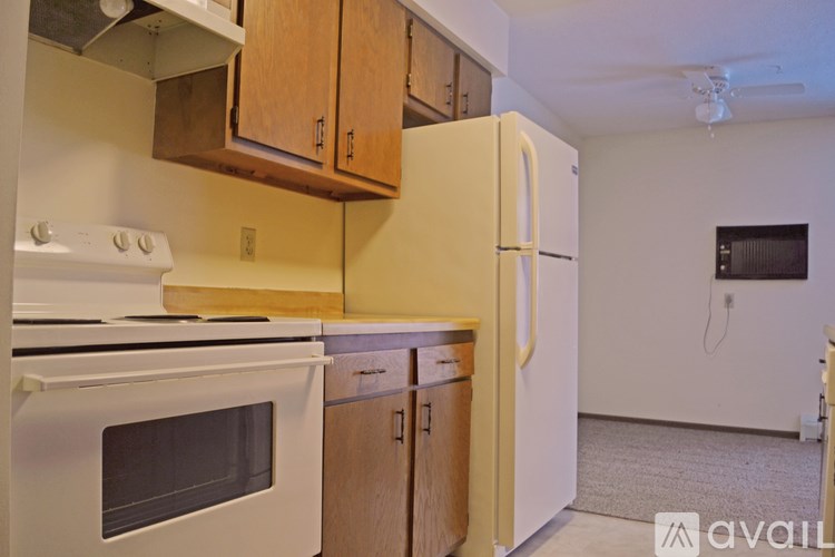 A kitchen with white appliances and wooden cabinets.
