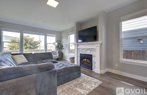 A living room with a grey couch and a fireplace.