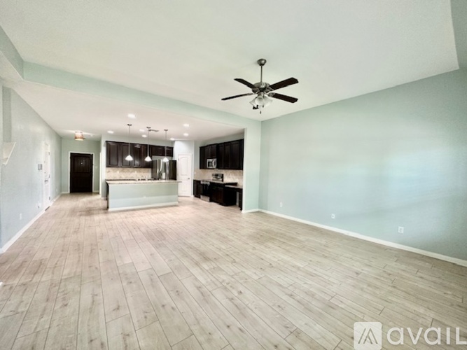 A spacious room with a ceiling fan and wooden flooring.